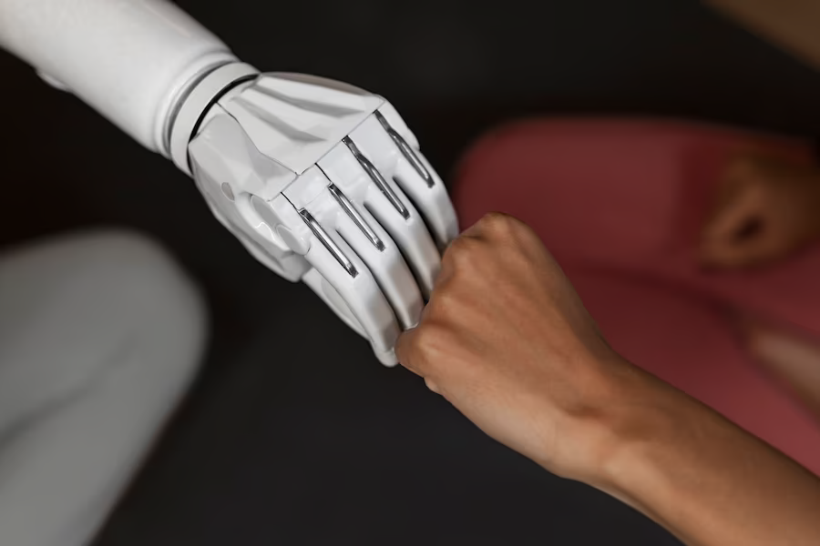 A robot hand and a human hand fist-bumping