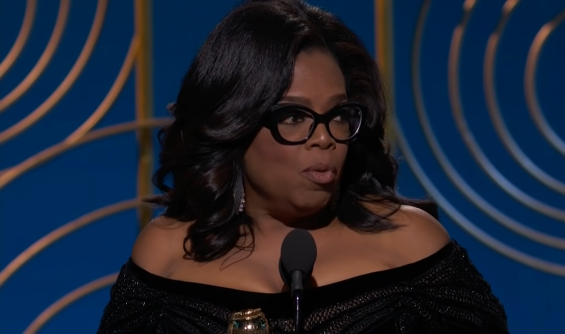 Oprah Winfrey in black dress and glasses on the stage