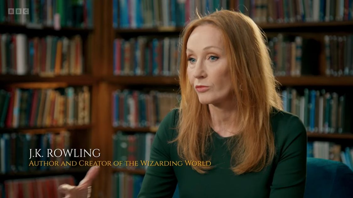 j.k. rowling in green dress and books on the shelves behind her