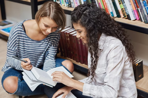 Two girls write something in a book